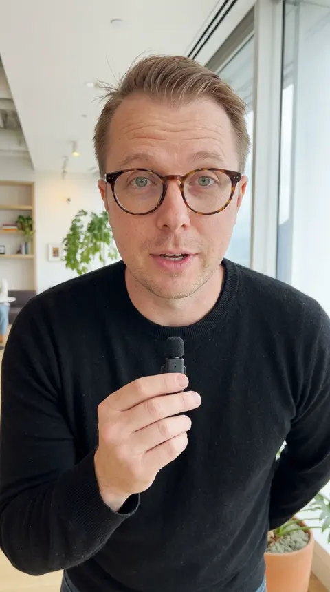 Paul's twin in a warm window room, mic in hand